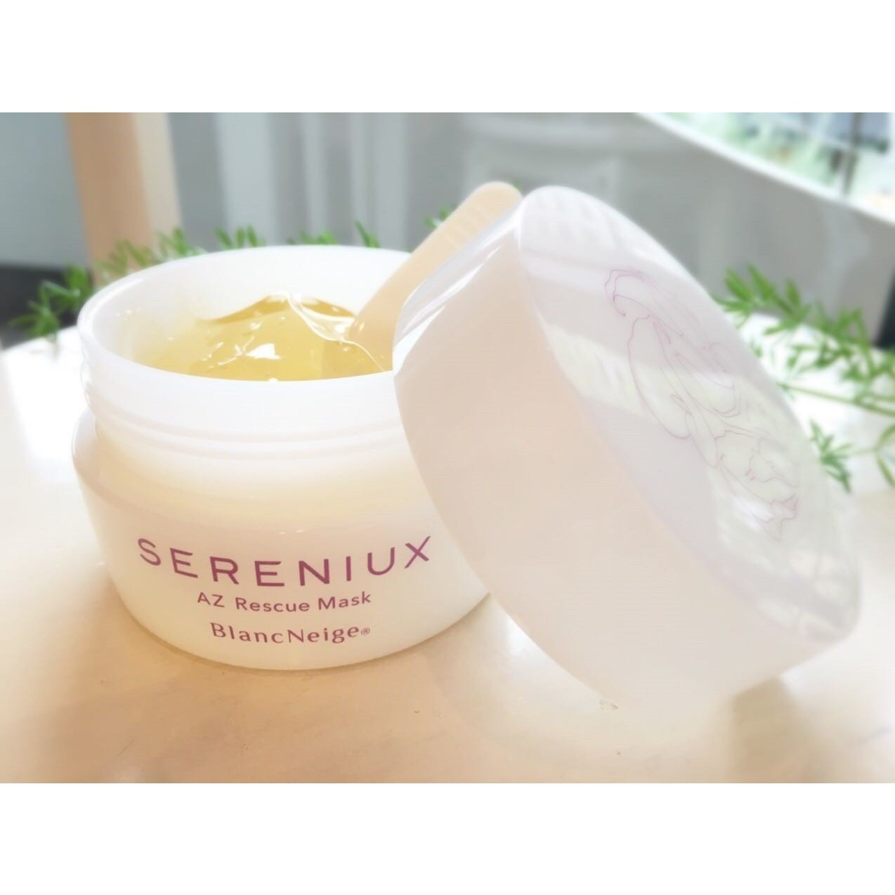 Cream-colored SERENIUX AZ Rescue Mask jar in the foreground, featuring the Blancskincare brand name. The product is showcased against a light background with some greenery visible.