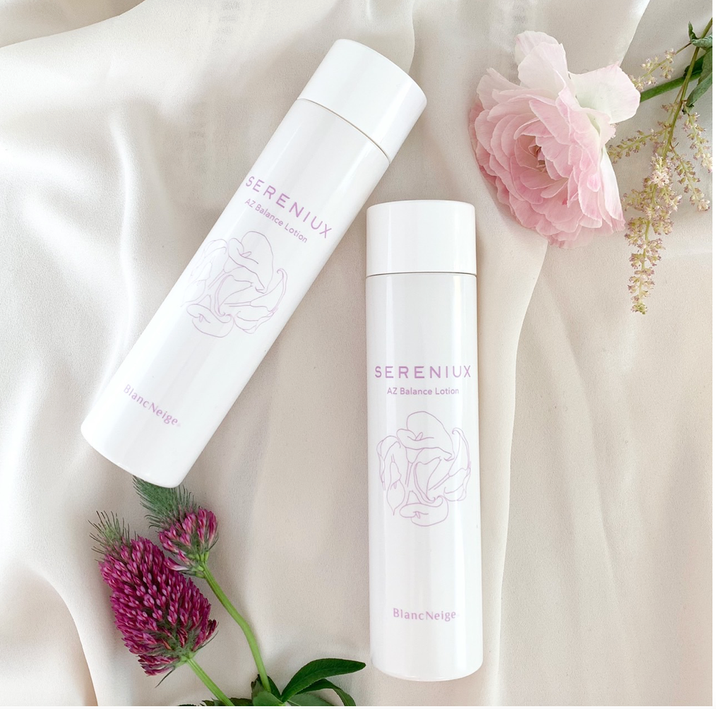 Elegant Japanese skincare products with floral accents, including a white Balance Lotion bottle and a pink rose on a soft, white fabric backdrop.