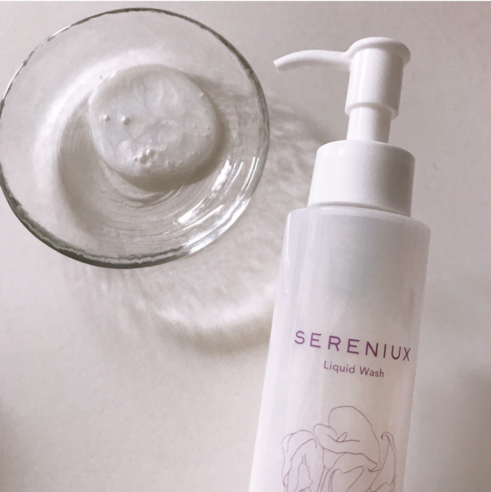 Sereniux series cleansing liquid wash in white bottle with floral design, surrounded by a glass container with a soft, smooth skin care product